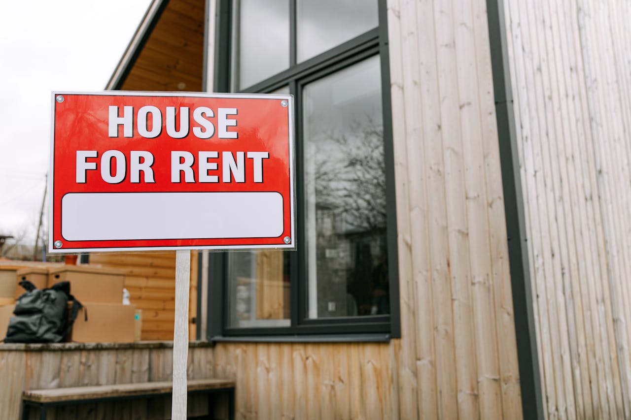Red House for Rent sign outside modern wooden house.