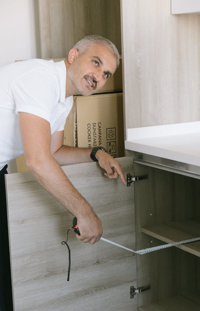 cta-bg Man in white shirt measuring kitchen cabinet with tape in Istanbul apartment. Ideal for real estate or DIY themes.
