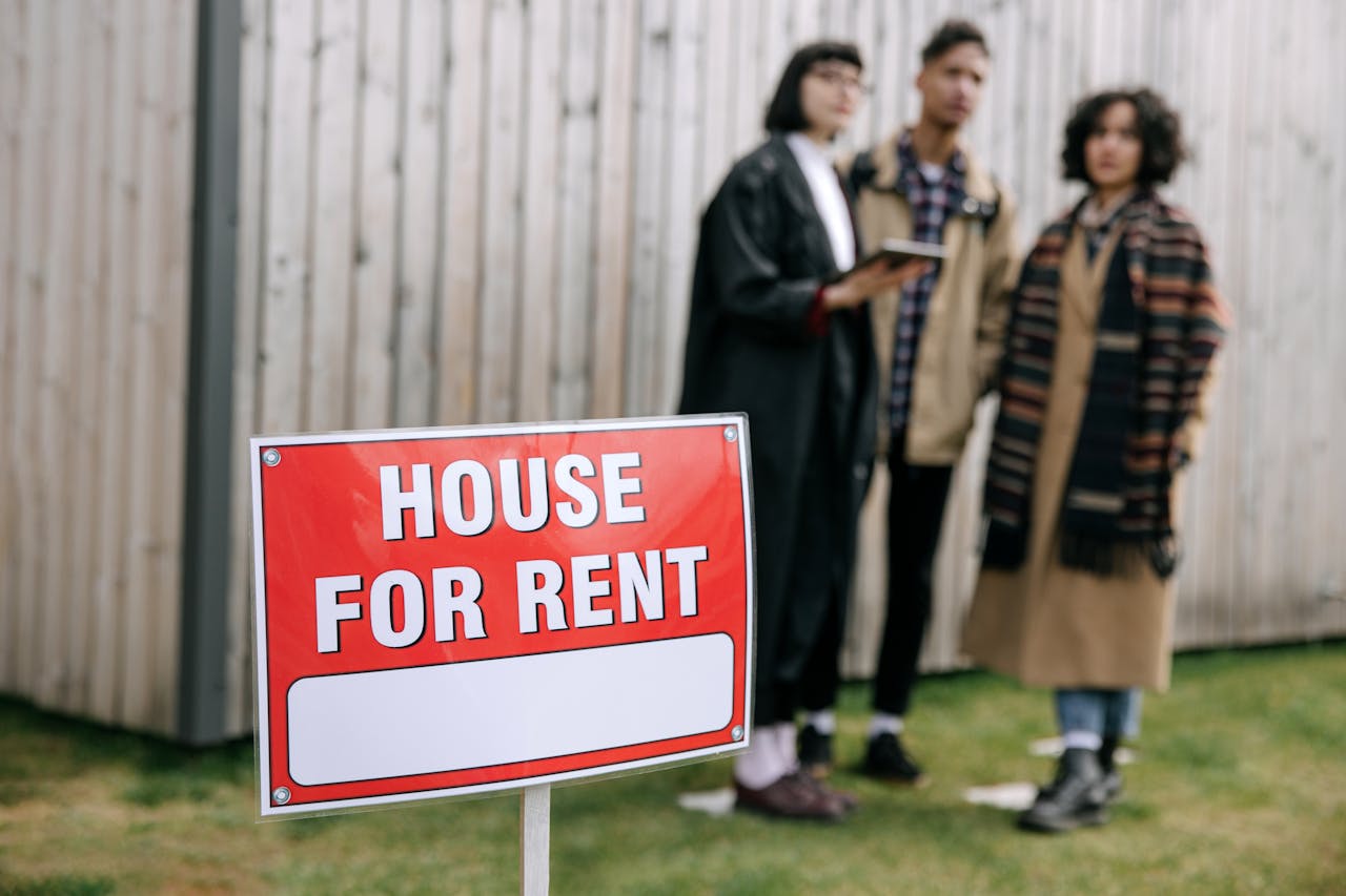 testimonials-img Three adults examining a house for rent sign outdoors, depicting diverse and inclusive interest in rental properties.